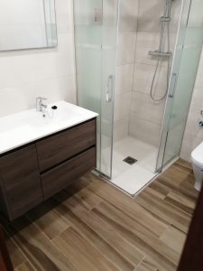 Reforma de baño realizada en La Rioja por instaladores especilistas con plato de ducha, mueble moderno y pavimento imitación a madera