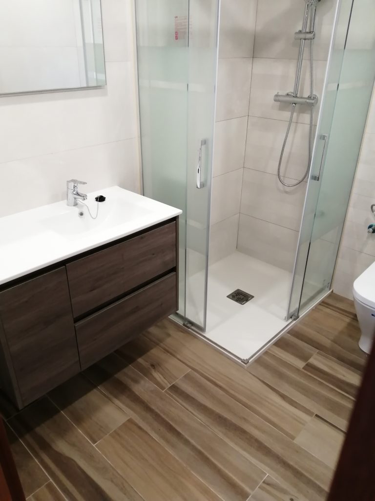 Reforma de baño realizada en La Rioja por instaladores especilistas con plato de ducha, mueble moderno y pavimento imitación a madera