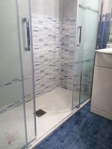 Renovar bañera por ducha con plato de mármol de 170X70 cm en color blanco, azulejo en color azul, subir las tomas a 1 metro de altura y mampara frontal Básic 2 fijos + 2 correderas