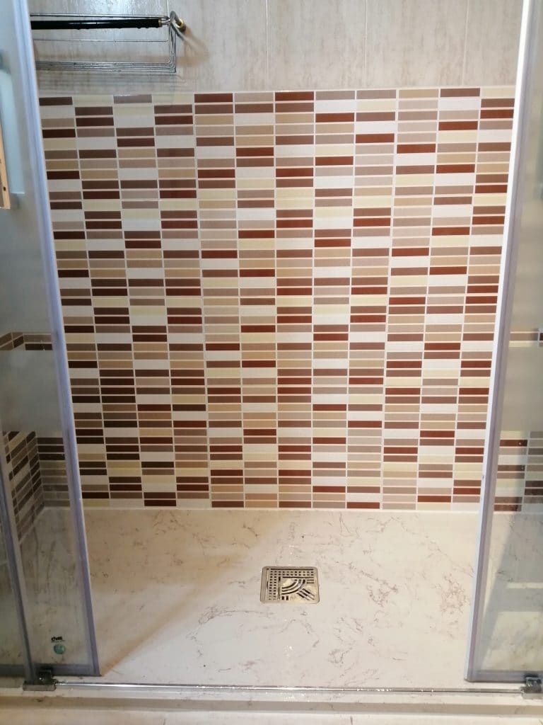 Reforma en Logroño con plato de ducha de mármol técnico color Coral con revestimiento cerámico en granate y mampara frontal