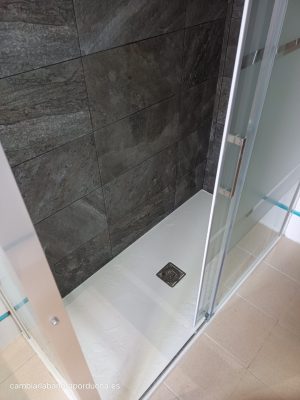 Plato de ducha de mármol técnico blanco contrastando con los azulejos negros de las paredes, mampara frontal conlateral fijo. Cambio realizado en Logroño