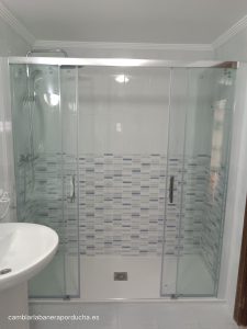 Cambio de bañera por ducha en Laguardia (Álava). Plato de ducha de mármol con azulejo azul en las tres paredes. Subir las tomas a 1 metro de latura. mampara frontal 2 fijos + 2 correderas