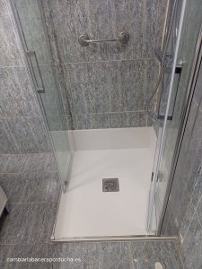 cambio de un plato de ducha por uno con un rodapié de mármol técnico y la instalación de una mampara plegable, brindando funcionalidad y un aspecto sofisticado al baño