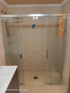 cambio de bañera por plato de ducha de mármol beige, acompañado de una elegante mampara frontal con dos paneles fijos y dos paneles correderos. Además, las tomas del grifo se han elevado a una altura de 1 metro, ofreciendo comodidad y accesibilidad en el baño