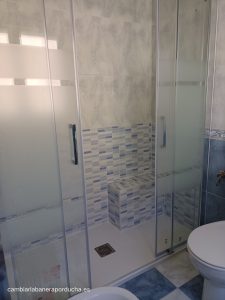 Cambio de bañera por ducha con asiento y azulejos con tonos azules Cambio de bañera por ducha en Nalda. Azulejos hasta media altura con azulejo tipo mosaico en azul. Mampara serigrafiada 2 fijos + 2 corredereas de la marca GME. El plato de ducha es de mármol blanco. En la esquina derecha de la foto, se observa un asiento para poder sentarse y poder dejar los accesorios de baño.