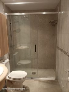 Esta imagen muestra una renovación de baño en la zona de Miribilla, Bilbao. Ducha a medida,se ha reemplazado la bañera por una amplia ducha a ras de suelo.La ducha está cerrada con puertas de vidrio transparente y cuenta con un elegante asa de cromo.El interior de la ducha está revestido con azulejos de tonos claros.