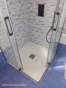 Renovación de baño en Lardero, La Rioja. Azulejos de mosaico azul en las paredes, mampara negra, ducha empotrada y nuevo plato de ducha. Espacio fresco y moderno con estilo y funcionalidad mejorada.