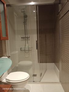 Cambio de plato de ducha por plato de ducha en Logroño con plato de ducha antideslizante de mármol crema coral, mampara de vidrio corredera y revestimiento de azulejos pequeños en tonos marrones