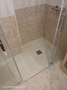 Cambio de bañera por un plato de ducha en Fuenmayor, La Rioja, mostrando un plato de ducha amplio con acabado en mármol claro y azulejos beige en las paredes, combinando azulejos grandes y pequeños para un efecto moderno. La instalación incluye mamparas de cristal correderas y un grifo de ducha monomando.