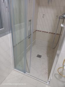 Instalación de un plato de ducha antideslizante en Vitoria-Gasteiz, con acabado en mármol claro y mamparas de cristal correderas. La ducha cuenta con paredes revestidas de azulejos blancos y una cenefa decorativa en tonos marrones, ofreciendo un diseño seguro y elegante.