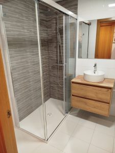 Cambio de bañera por ducha en Logroño con plato blanco a ras de suelo, mampara de cristal, ducha efecto lluvia y mueble suspendido de madera